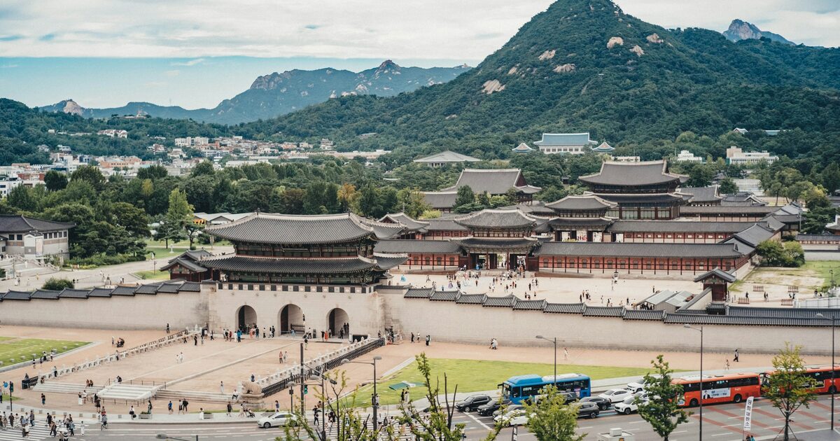 Gwanghwamun gate and the halls of Gyeongbokgung Palace in daylight, with the green peak of Bugaksan rising behind them