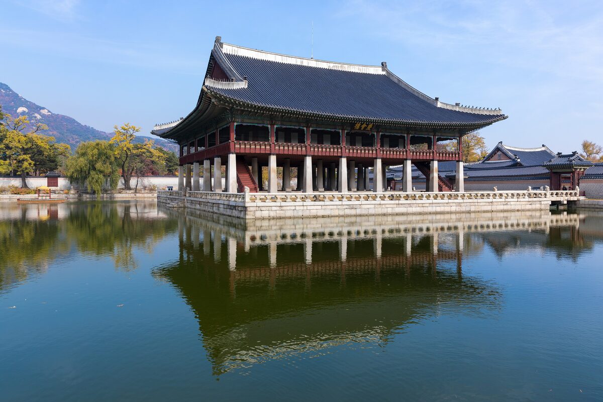 Gyeonghoeru pavilion on its stone base above the still lotus pond in Gyeongbokgung, reflected in the water