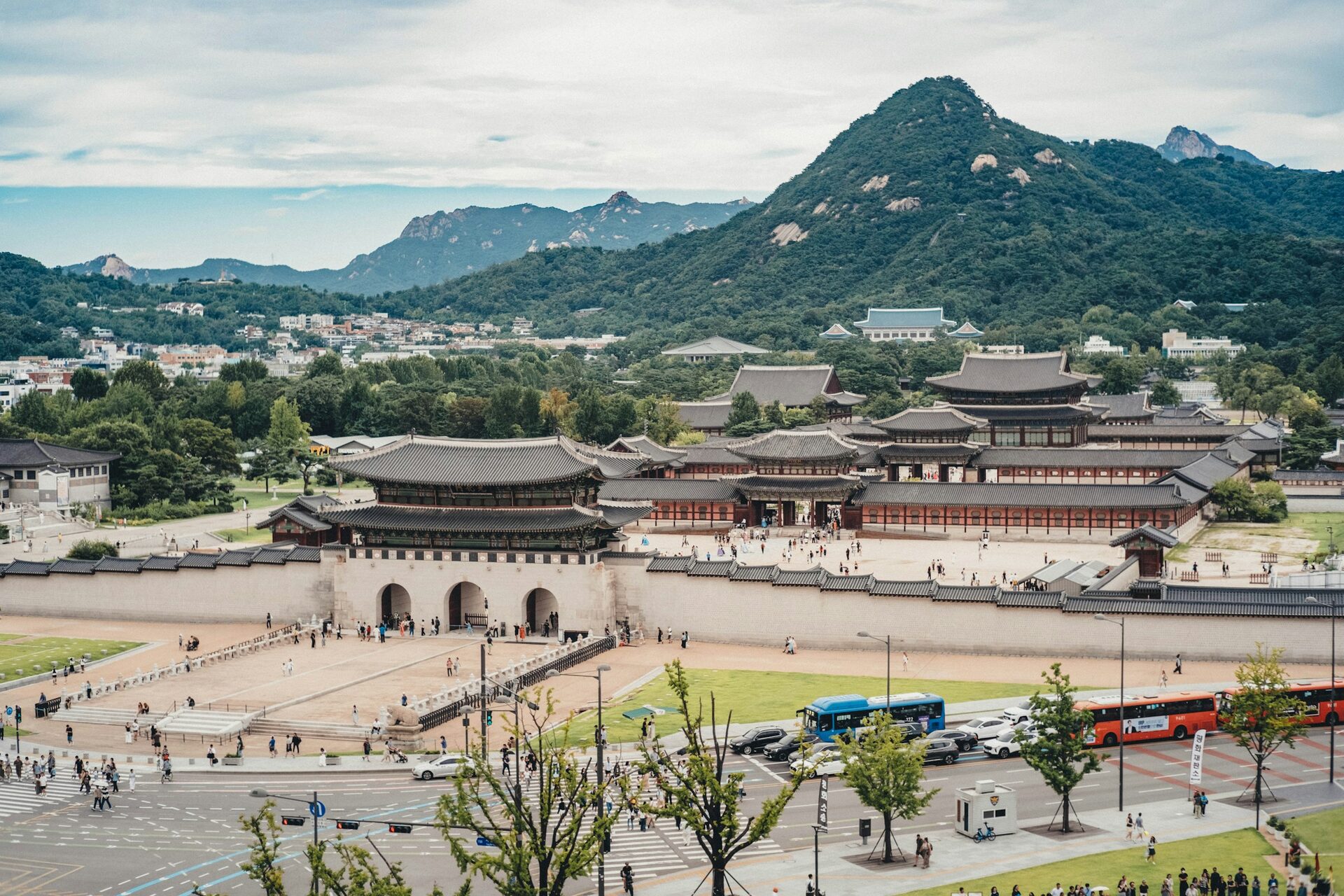 Gwanghwamun gate and the halls of Gyeongbokgung Palace in daylight, with the green peak of Bugaksan rising behind them