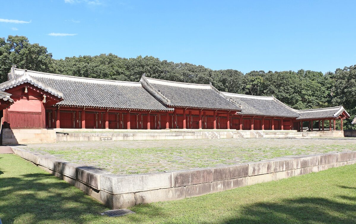 The long red Yeongnyeongjeon hall of Jongmyo Shrine on a stone platform, with a lawn in front