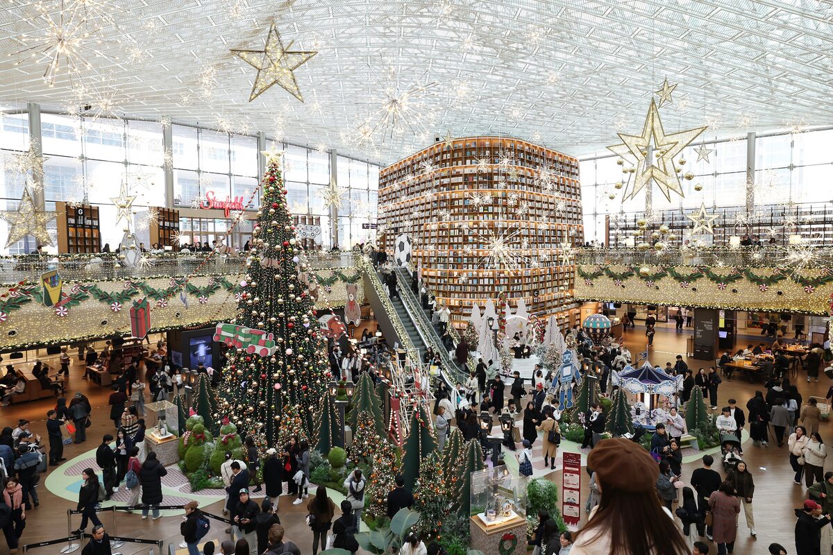 The tall cylindrical wall of books inside the Starfield Library at COEX, under a glass ceiling with holiday decorations