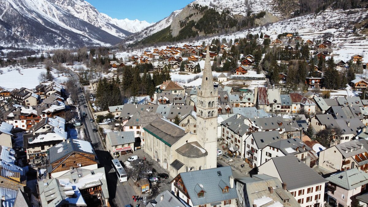 Aerial view of Le Monêtier-les-Bains in snow, with the church tower in the middle of the village