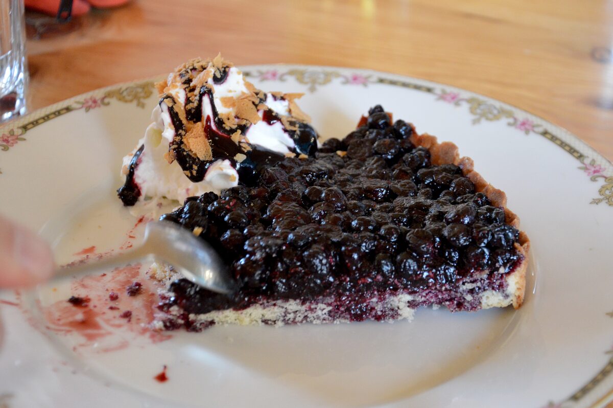 A slice of blueberry tart with whipped cream on a plate
