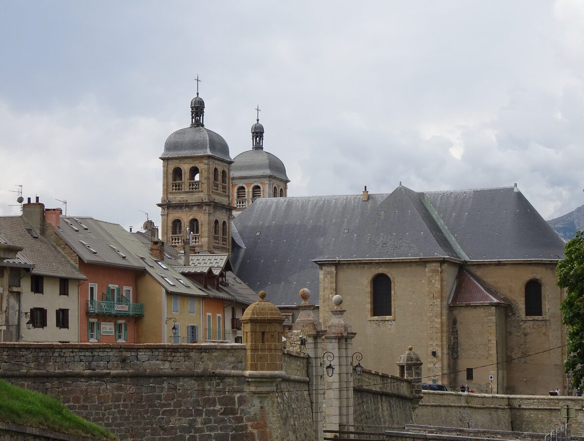 The twin bell towers of the Collégiale Notre-Dame-et-Saint-Nicolas rising above the roofs of Briançon