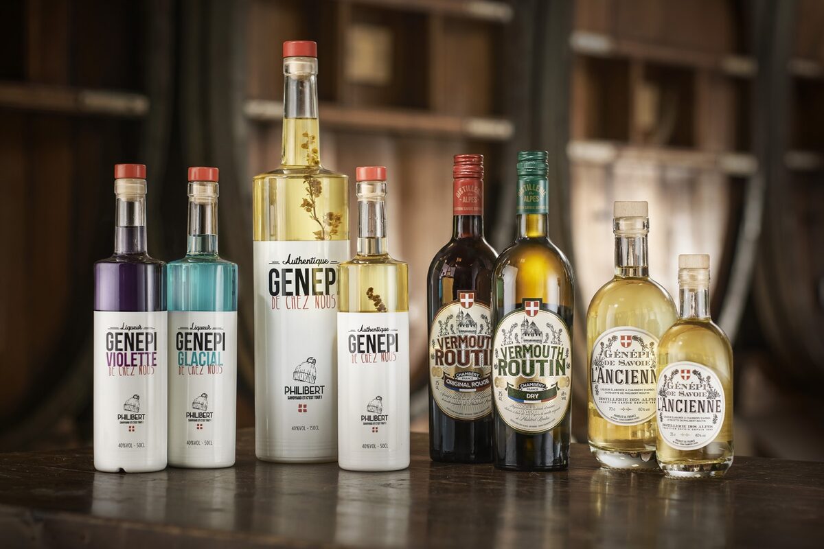 A row of génépi and vermouth bottles, the Alpine herbal liqueur, on a dark wooden table