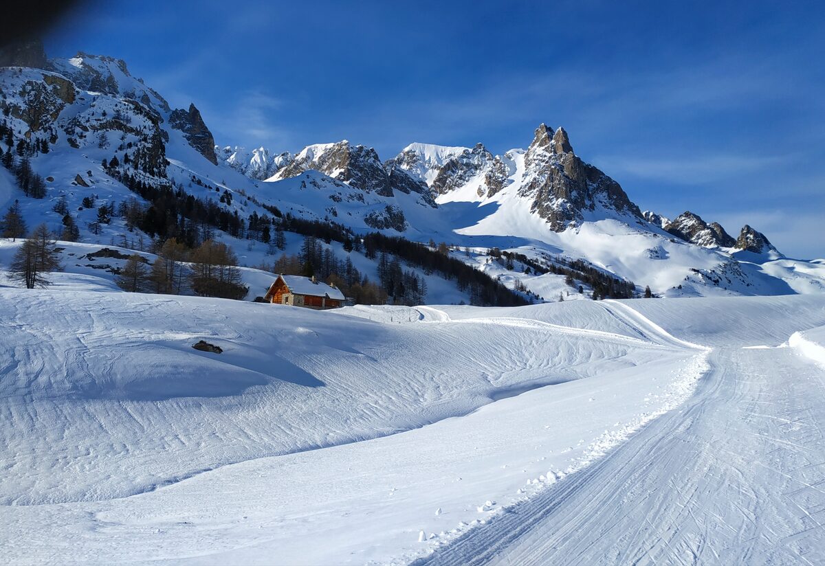 A snowy cross-country skating piste in the Névache valley with the mountains behind