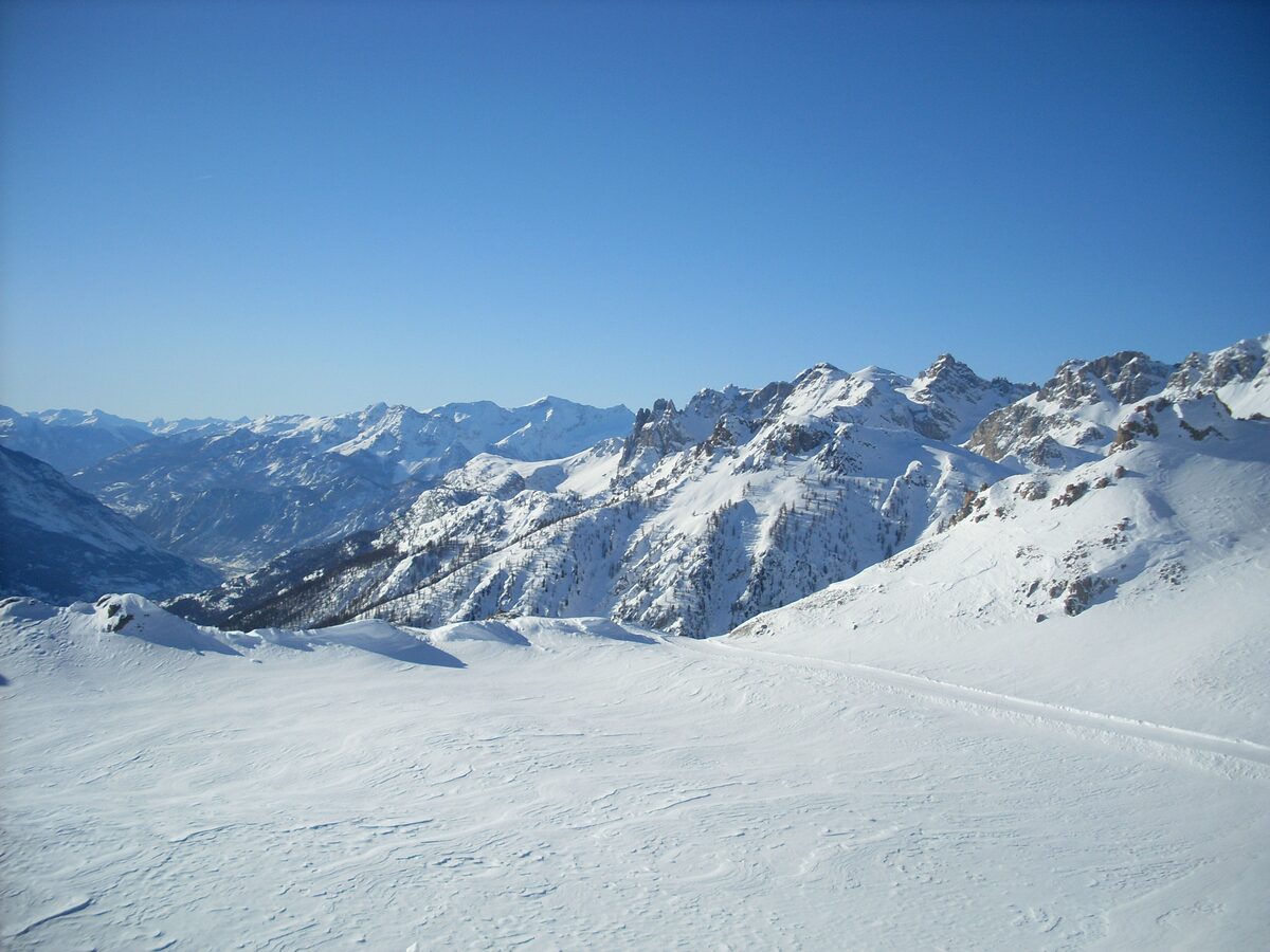 Snowy ridges and a groomed track across the high snowfield of the Serre Chevalier ski area