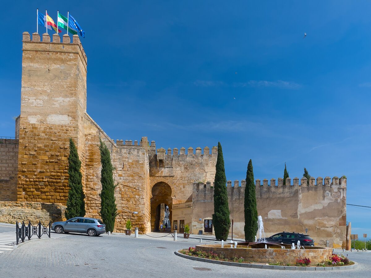 The massive stone walls and towers of the Puerta de Sevilla in Carmona under a blue sky
