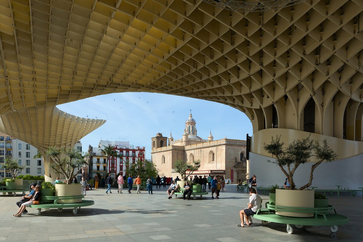 The undulating wooden canopy of the Metropol Parasol over Plaza de la Encarnación, framing a church dome beyond