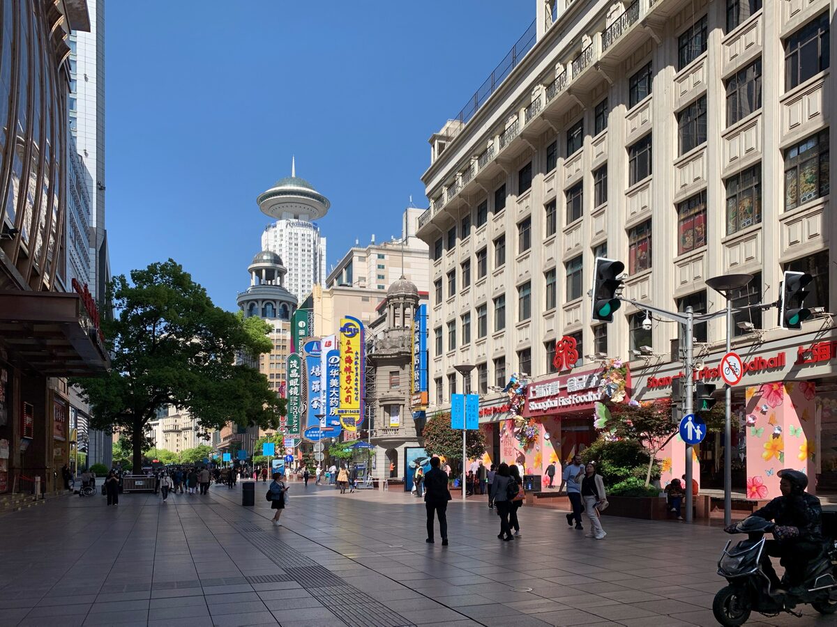 The pedestrian stretch of East Nanjing Road on a sunny morning, with neon signs and old department store buildings