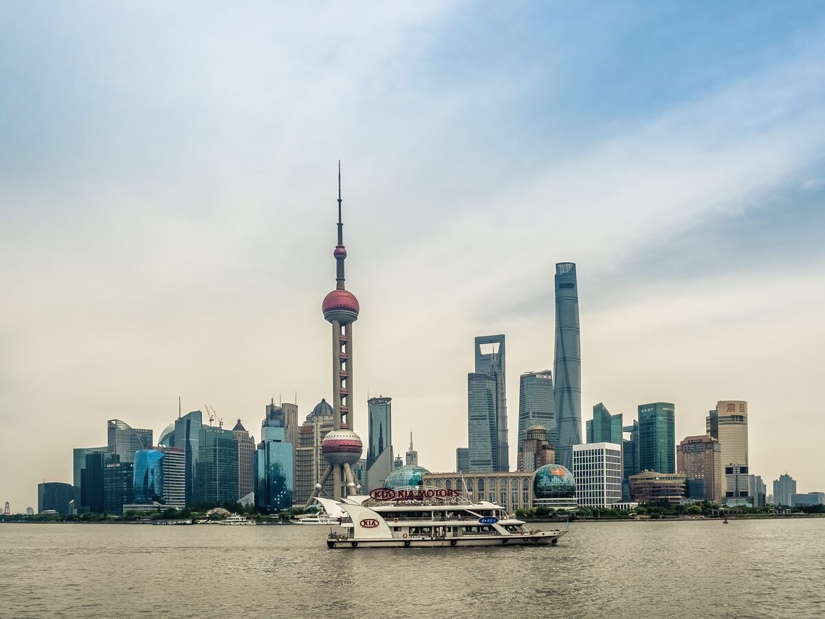 The Pudong skyline across the Huangpu River with a tour boat in front, the Oriental Pearl Tower and the Shanghai Tower behind