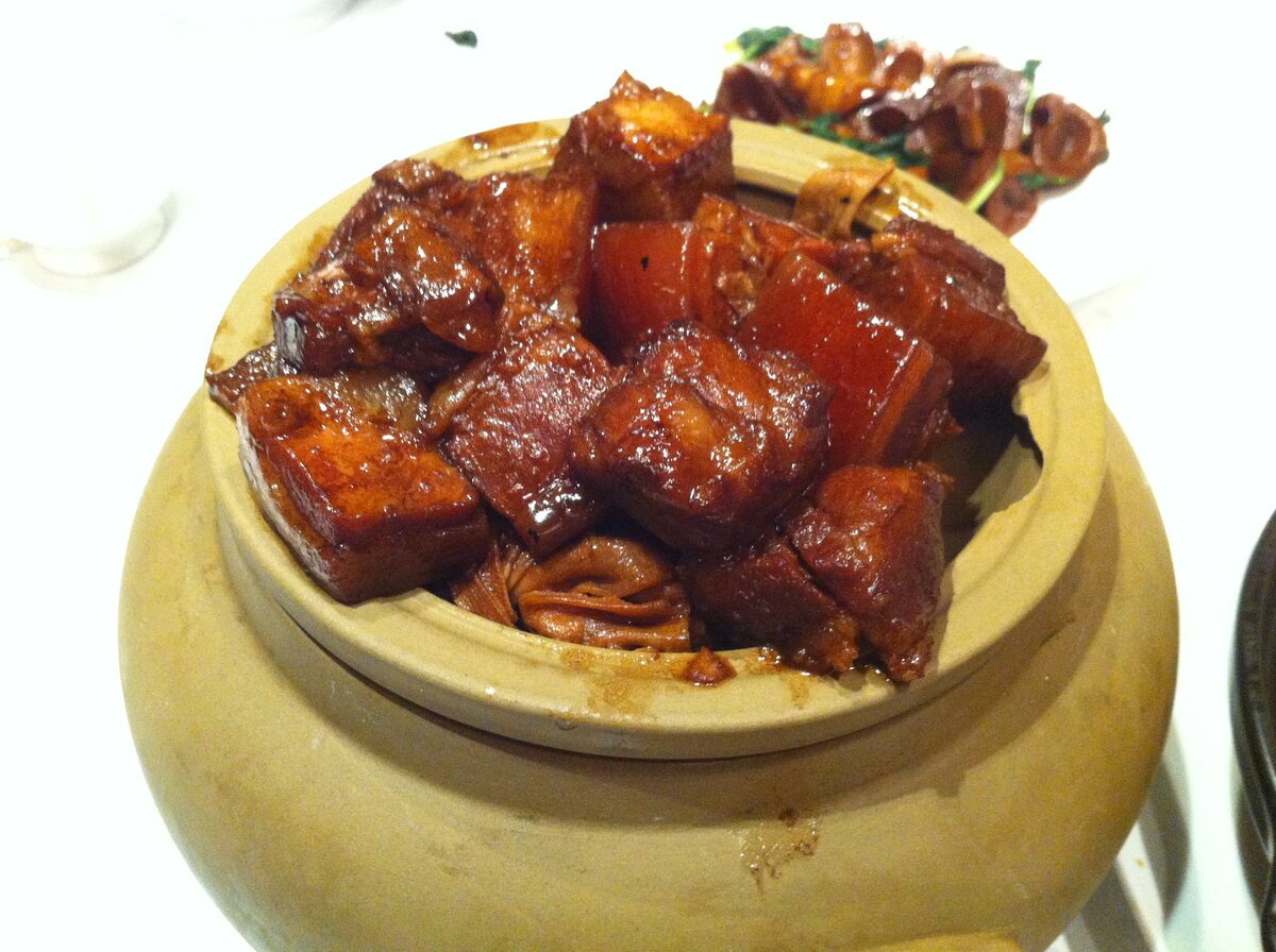 Glossy cubes of red-braised pork belly in a clay pot