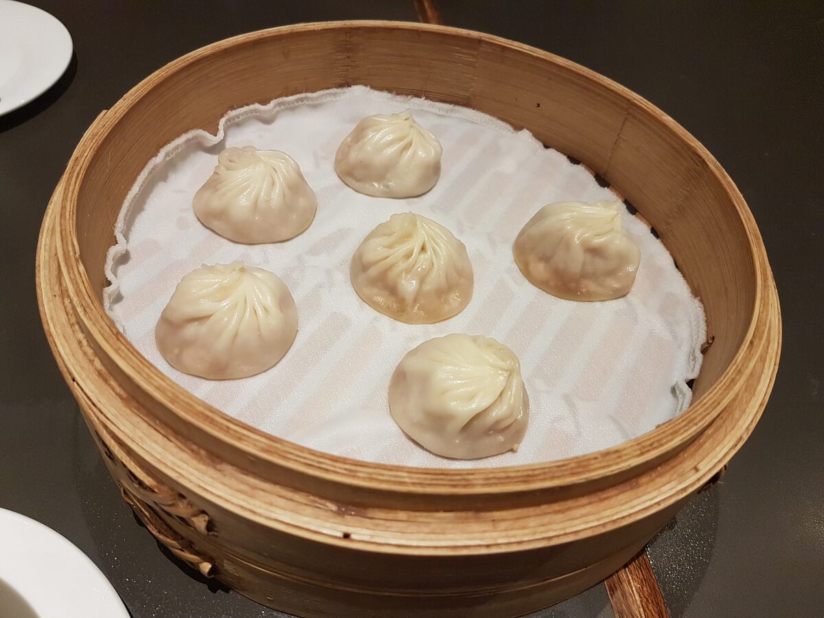 A bamboo steamer with six xiaolongbao soup dumplings