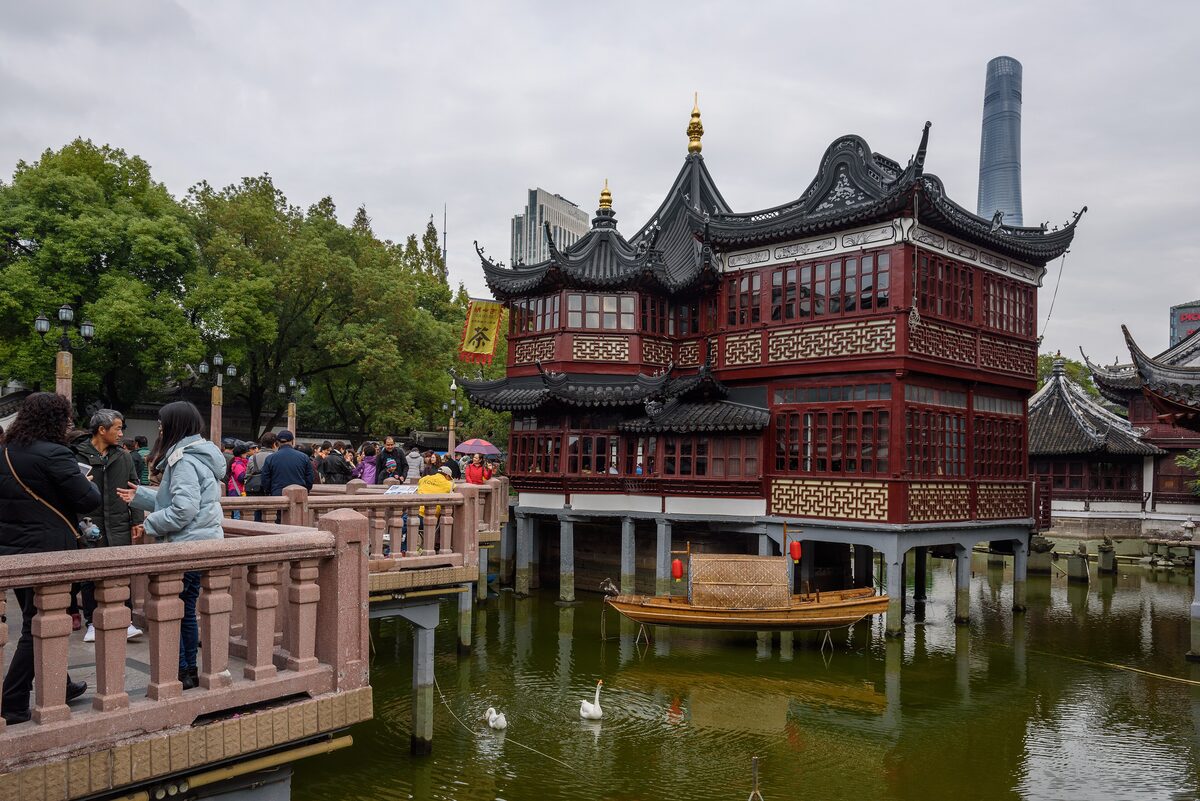 The two-tier Huxinting teahouse on its pond at the Yuyuan Bazaar, with the Shanghai Tower rising behind