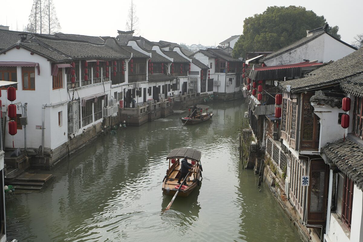A small boat on the canal between white-walled houses with red lanterns in Zhujiajiao