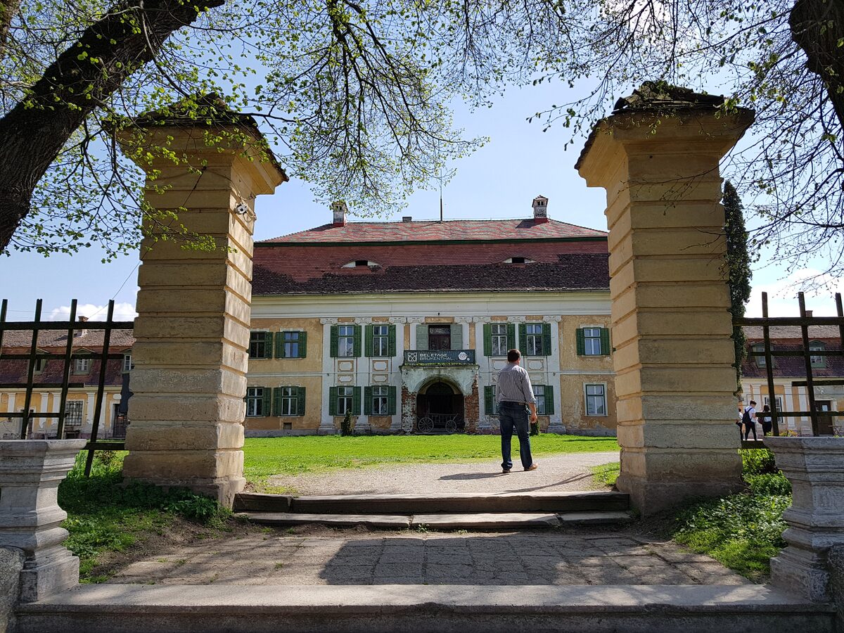 The yellow baroque Brukenthal summer palace at Avrig, seen through the stone gate pillars of its garden