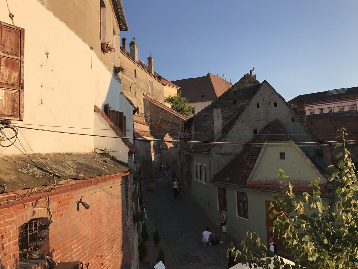 Evening light on the Passage of Stairs, a narrow cobbled lane under old walls and steep-roofed houses leading down to Sibiu's Lower Town