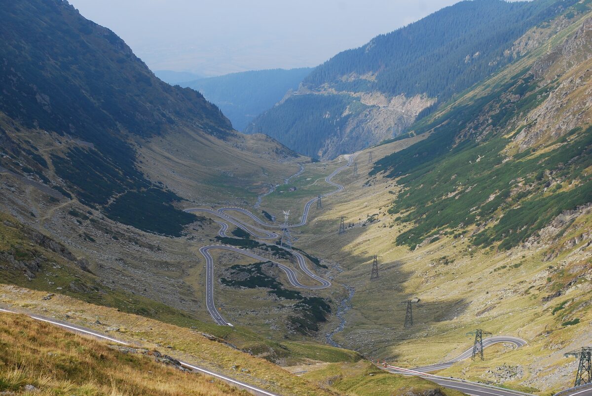 The Transfăgărășan road winding in hairpin bends down a green mountain valley from Bâlea Lake