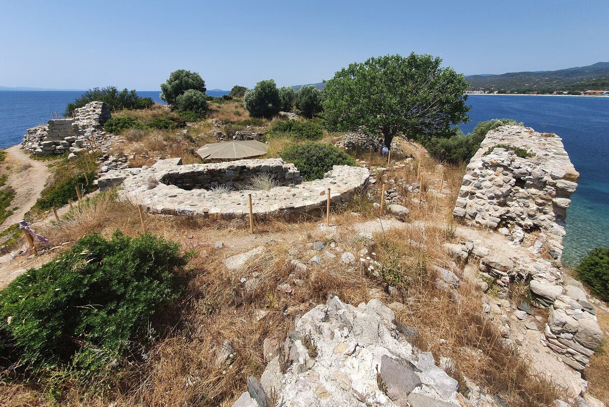 Stone walls and a round foundation on the Lekythos headland at Toroni, with the sea on both sides and the coast stretching away