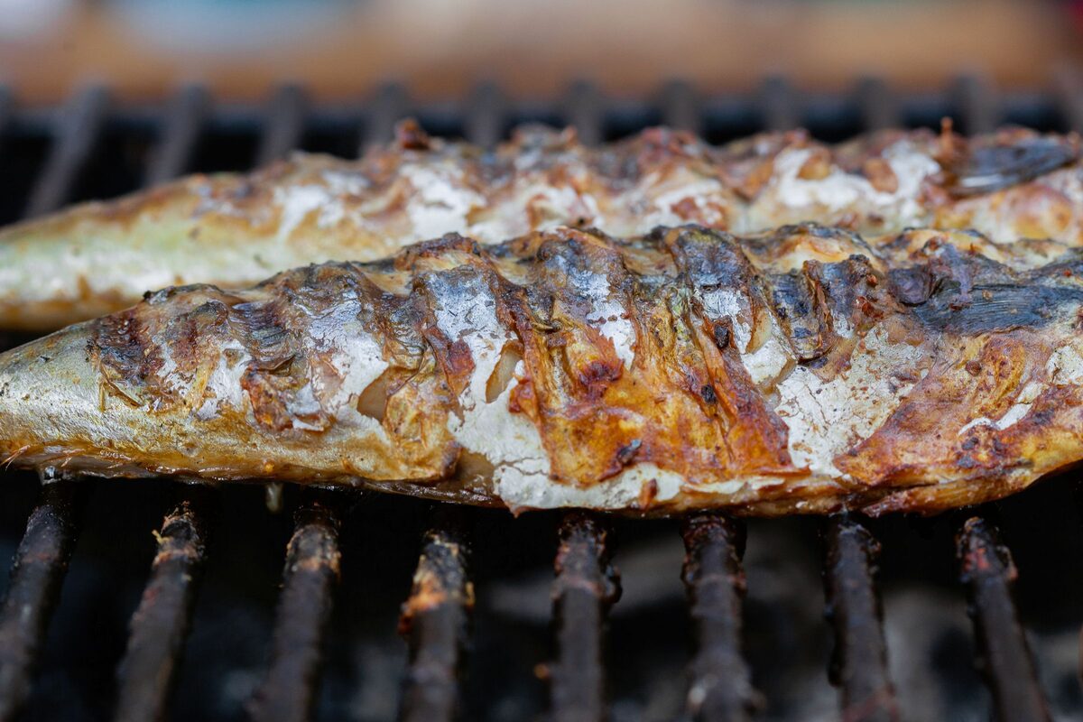 Two whole fish grilled over charcoal, the skin blistered and golden