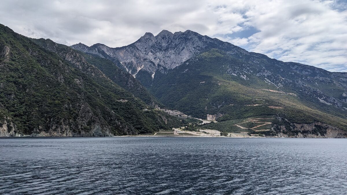 The steep western slope of Mount Athos, a wooded mountain rising above calm water