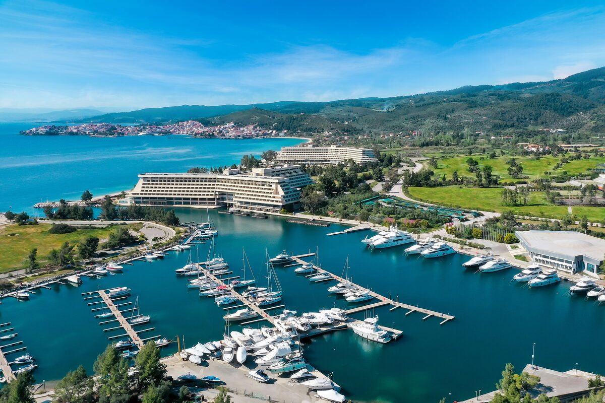 Aerial view of the Porto Carras marina, with yachts in the basin and a large resort hotel beside green lawns