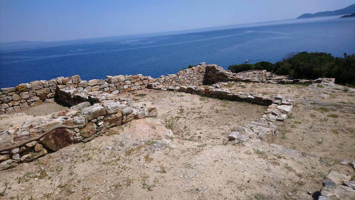 Low stone foundations of ancient houses on a hillside above the sea at Stageira