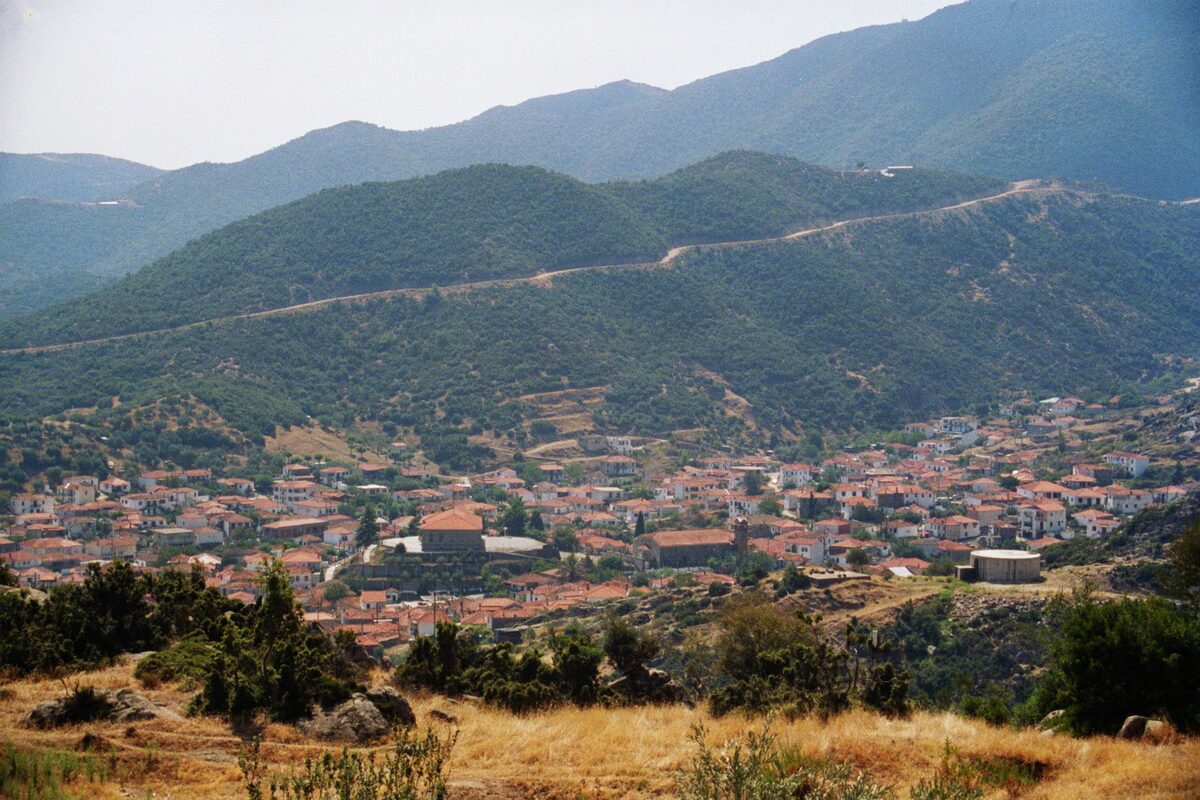 The village of Sykia seen from the hillside, red roofs spreading across the valley below wooded mountains