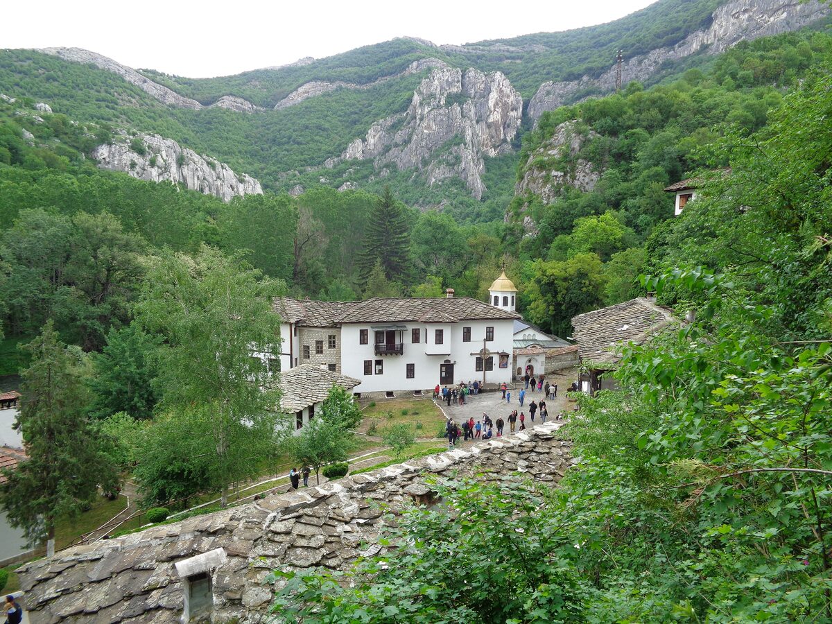 Cherepish Monastery's white buildings in a green valley of the Iskar Gorge beneath pale limestone cliffs.
