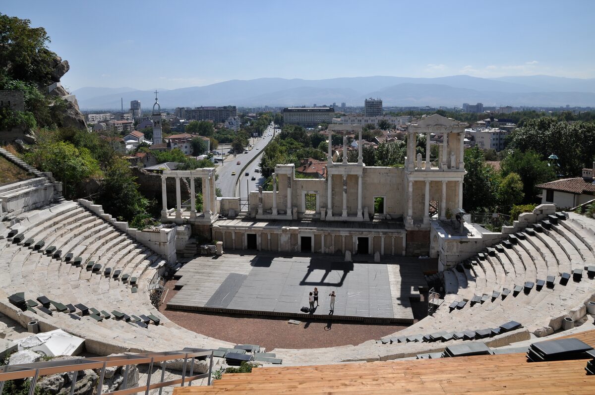 The marble tiers and columned stage building of the Roman theatre of Plovdiv, looking out over the city towards the Rhodope Mountains.
