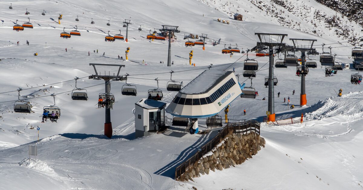 The Hainbachkar chairlift station in Sölden, with orange chairs and skiers on the snowy pistes around it