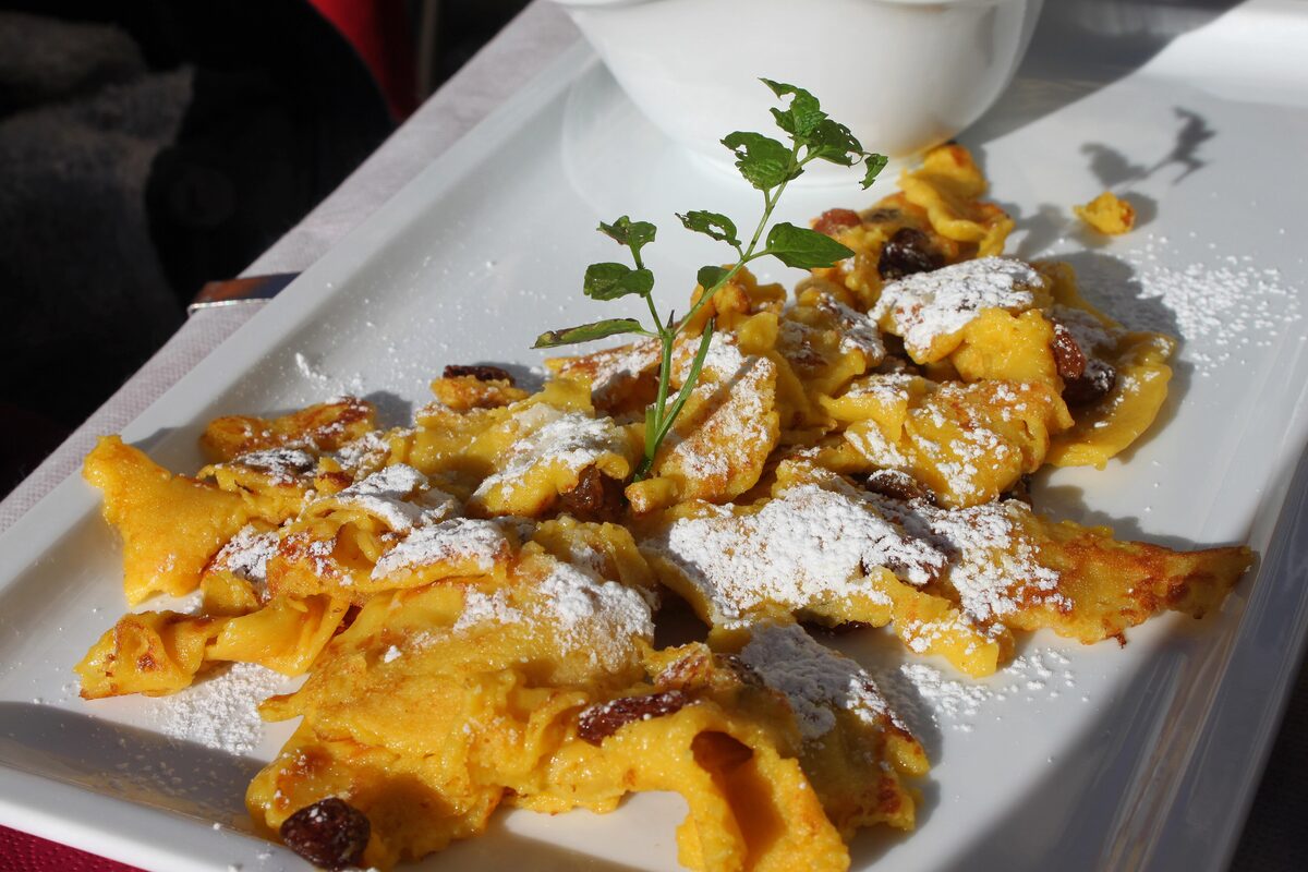 Kaiserschmarrn torn into pieces, dusted with icing sugar, with raisins and a sprig of mint on the plate