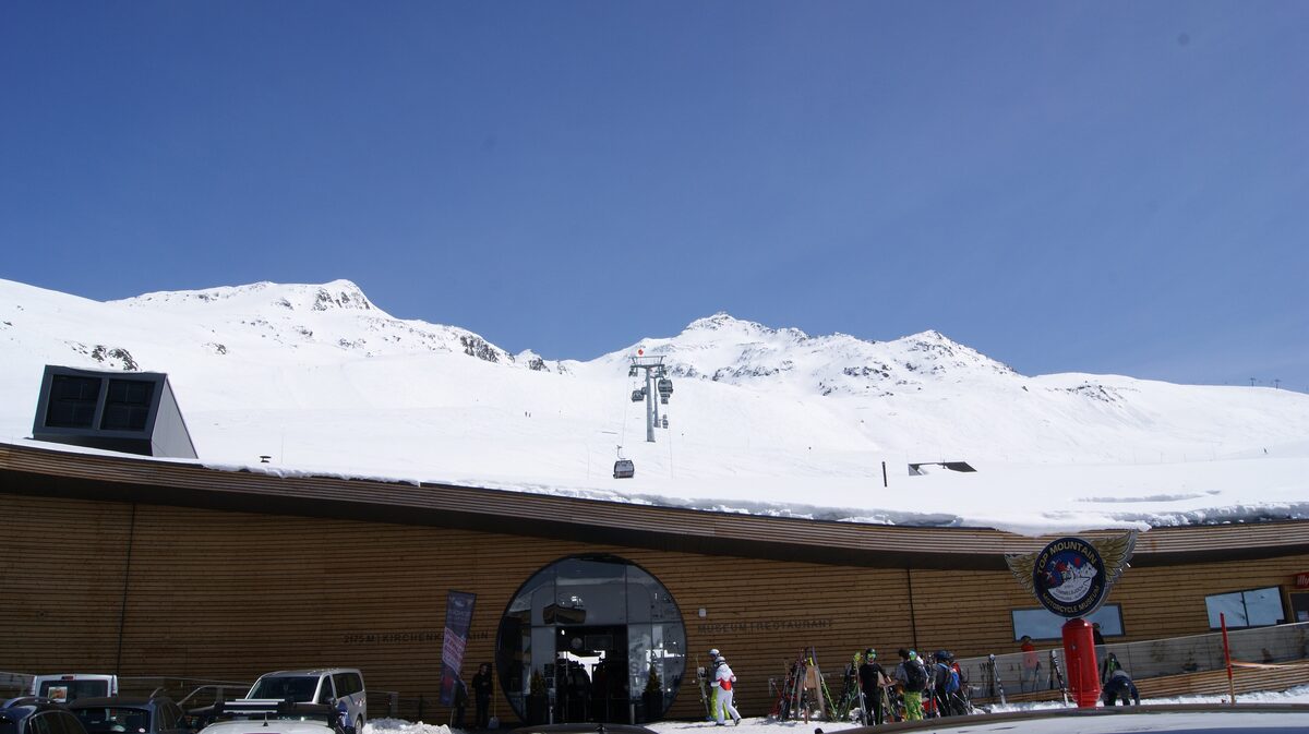 The timber-clad Top Mountain Crosspoint building at the Kirchenkar lift in Hochgurgl, with a gondola line rising behind it and skiers at the entrance