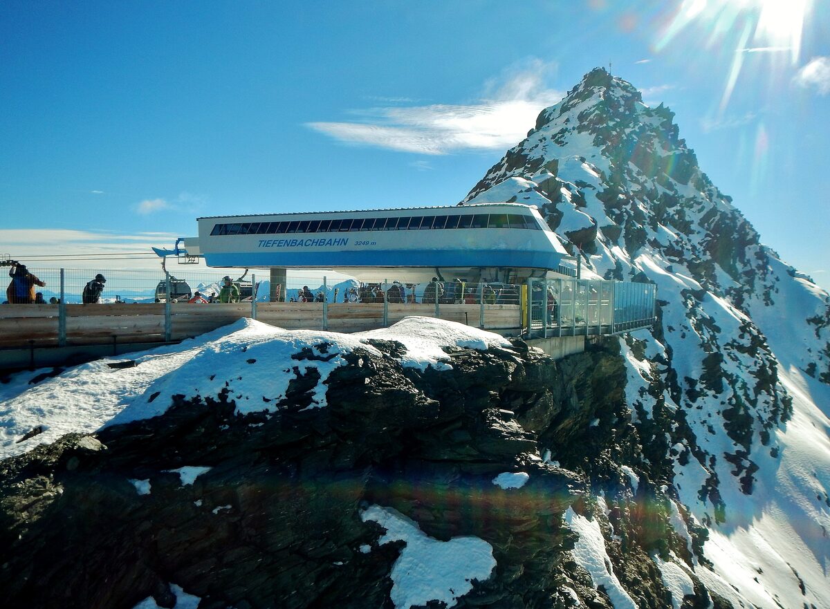 The Tiefenbach gondola top station on a rocky, snow-dusted summit under a blue sky