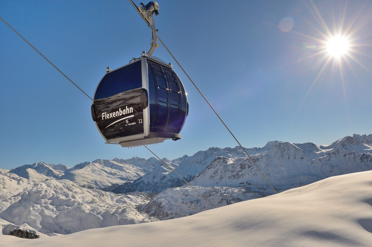 A Flexenbahn gondola cabin in the sun above the snowy mountains of the Arlberg
