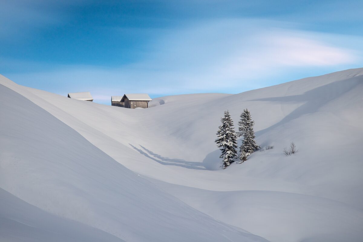 Snow-covered hills and mountains on the Hochtannberg pass, with a few huts in the snow