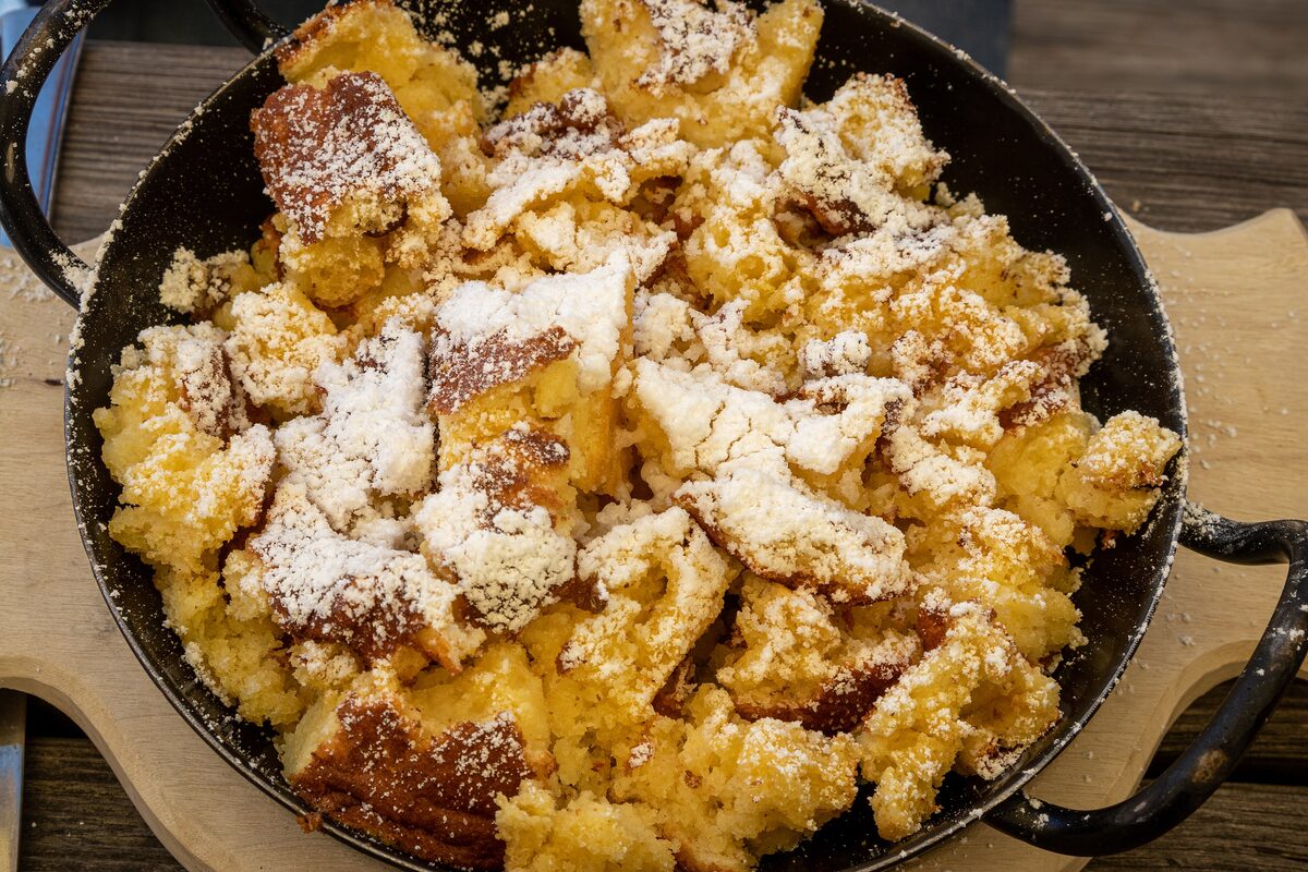 Kaiserschmarrn torn into pieces in a pan and dusted with icing sugar