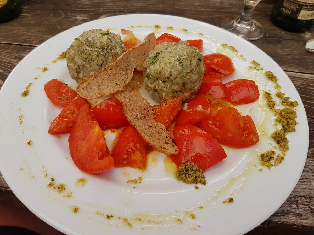 Two herb dumplings on sliced tomatoes with a green dressing