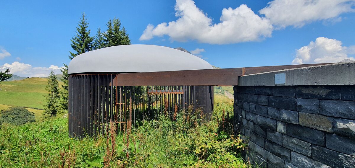 James Turrell's Skyspace above Lech in summer, a stone chamber with a pale dome and a rusty steel screen on a green hillside