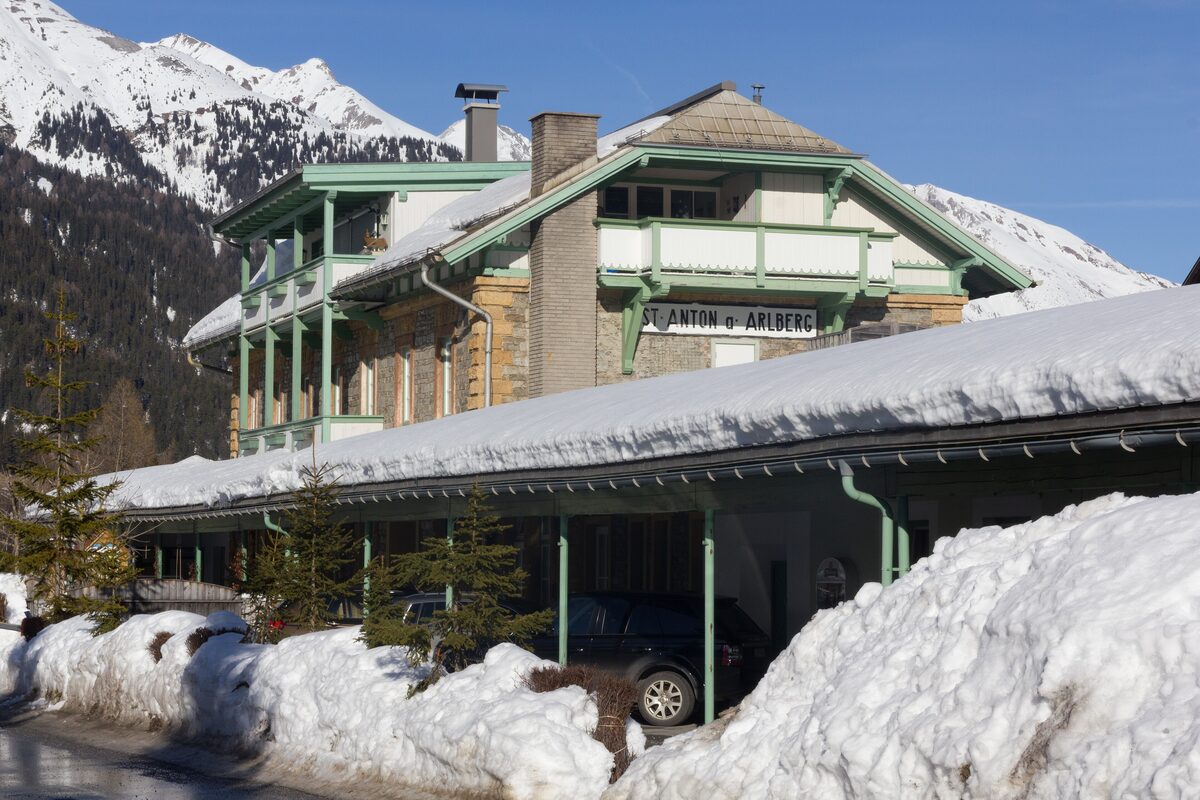 The old railway station of St. Anton with green wooden balconies and a heavy load of snow on its roof