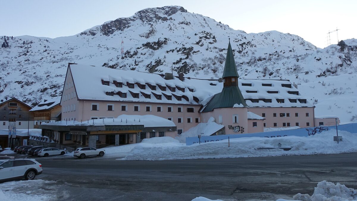 The Arlberg Hospiz hotel at the pass in winter, with its church tower and snow on the road