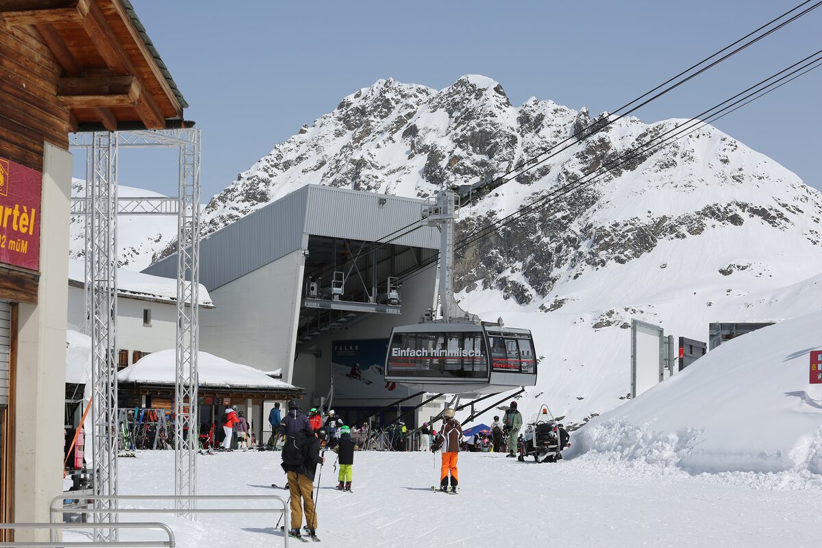 Skiers outside the Murtèl mid-station of the Corvatsch cable car, with snowy peaks above