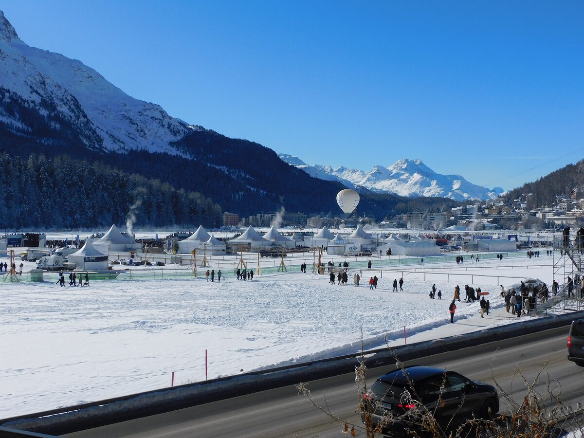 A hot-air balloon over the frozen Lake St. Moritz, with tents and visitors on the ice during the ice event