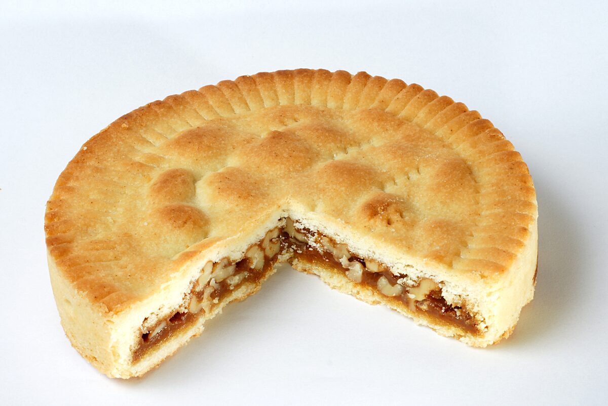 A sliced Engadiner Nusstorte showing its caramelized walnut filling under a golden shortcrust lid