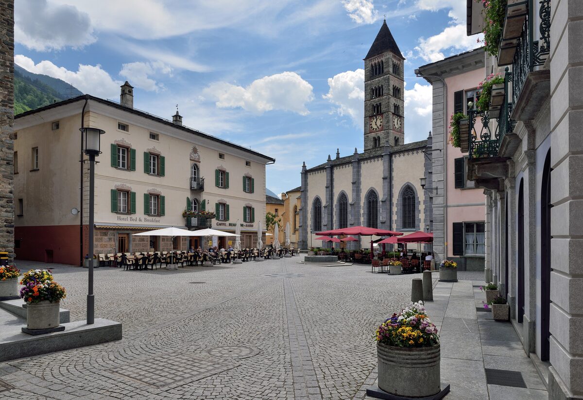 Poschiavo's cobbled main square with cafe terraces and the collegiate church tower