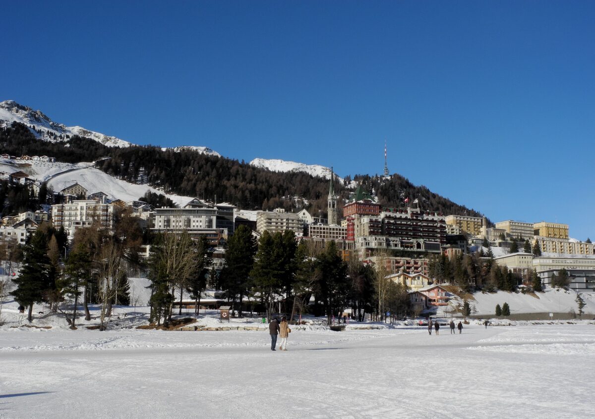 The St. Moritz village hotels above the frozen lake, with people walking on the ice in winter
