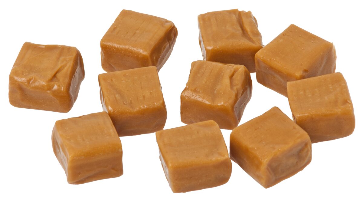 Ten squares of soft caramel candy on a white background