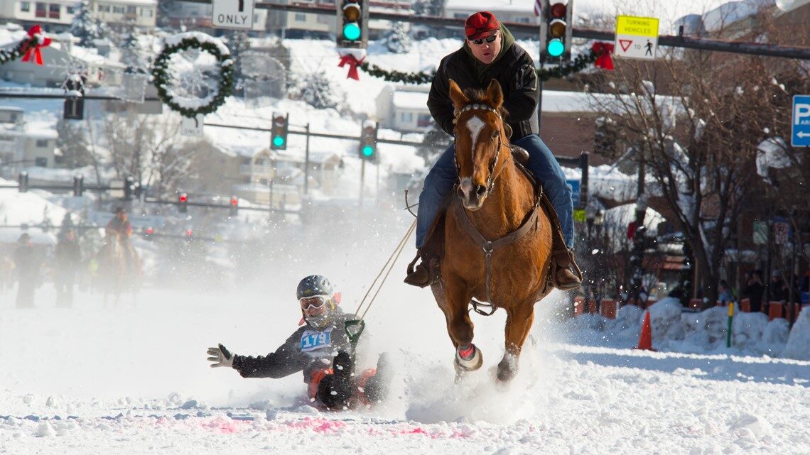 Skijoring downtown during Winter Carnival, wreaths hanging over the snowy street