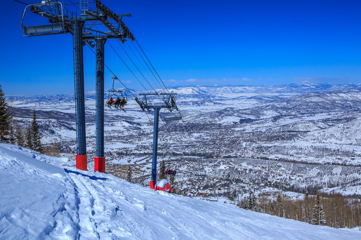 A chairlift climbs above the snowy valley beside a groomed ski run