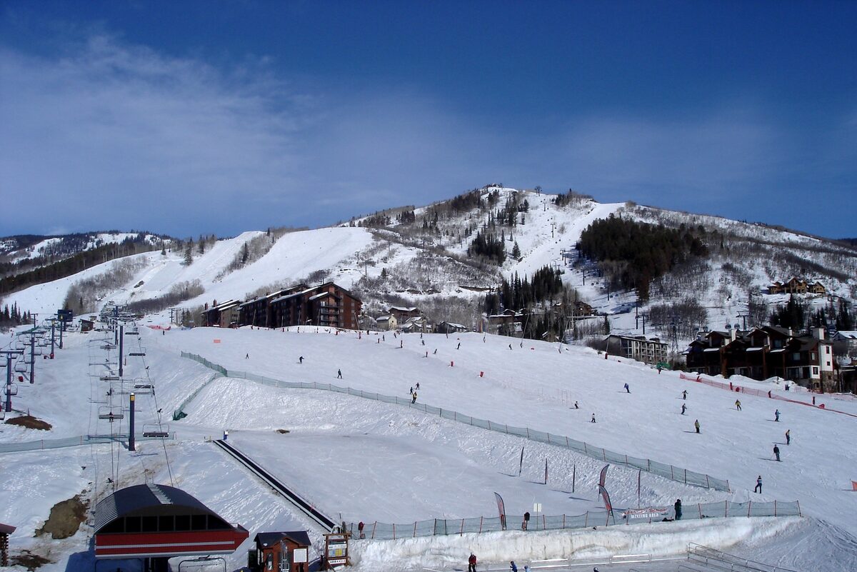 Skiers on a beginner slope beside a lift terminal at the base